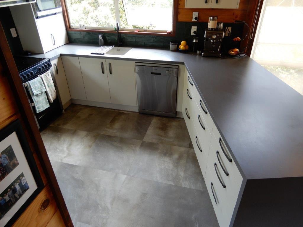 A kitchen with white cabinets and a black counter top