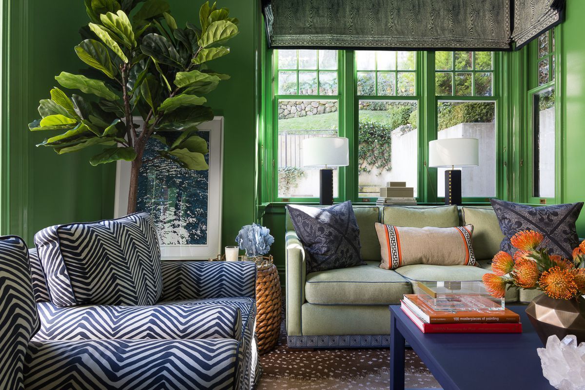 A living room with green walls and blue and white furniture
