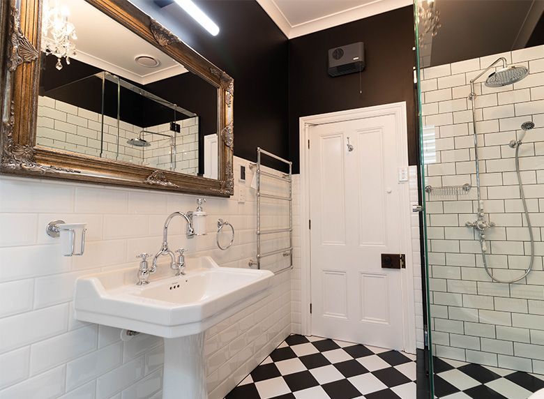 A bathroom with a sink , mirror , shower and checkered floor.