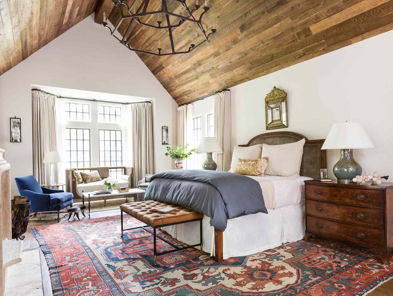 A bedroom with a bed , dresser , nightstand and rug.