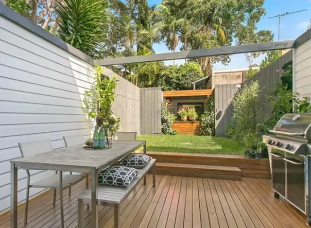 A patio with a table and chairs and a grill