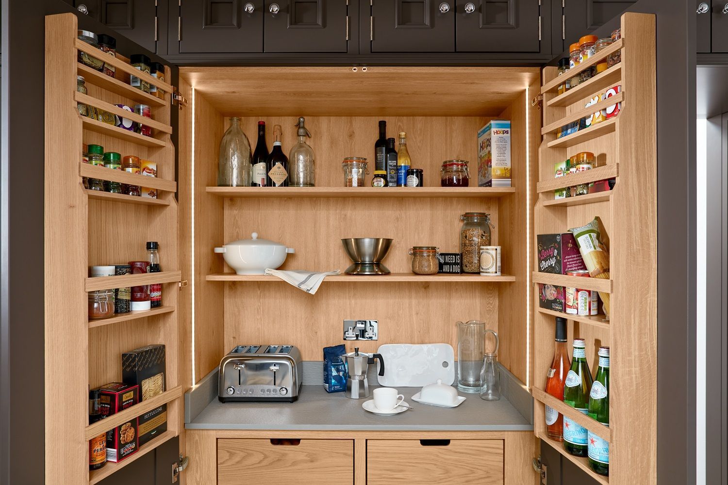 A kitchen pantry with wooden shelves and drawers and a toaster oven.