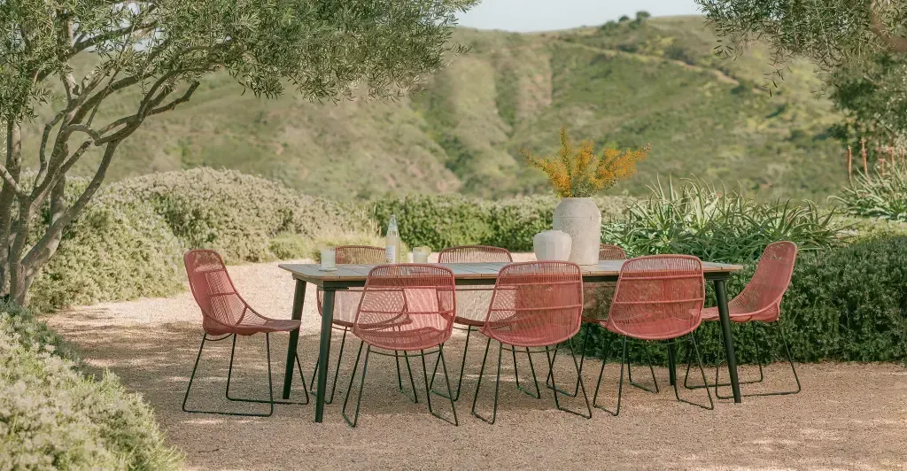 A table and chairs are sitting under a tree in a garden.
