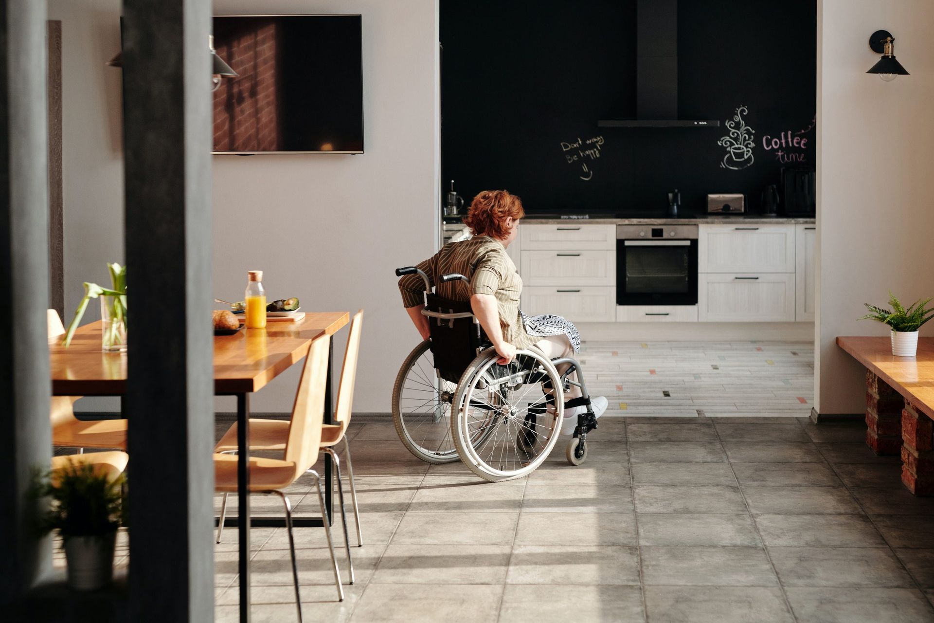 A woman in a wheelchair is sitting in a kitchen.