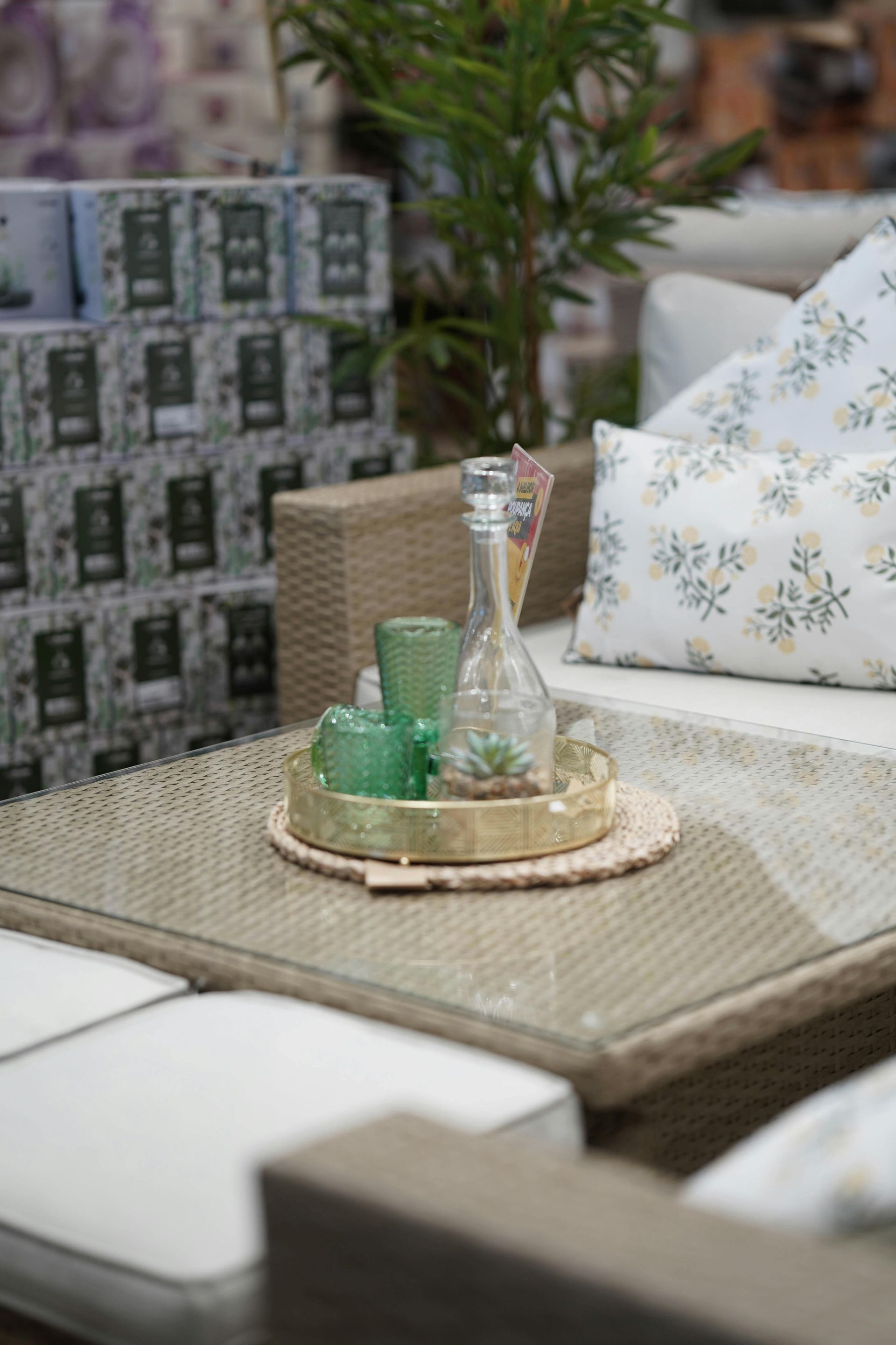 Outdoor patio seating with woven table, tray of green glasses, and floral cushions