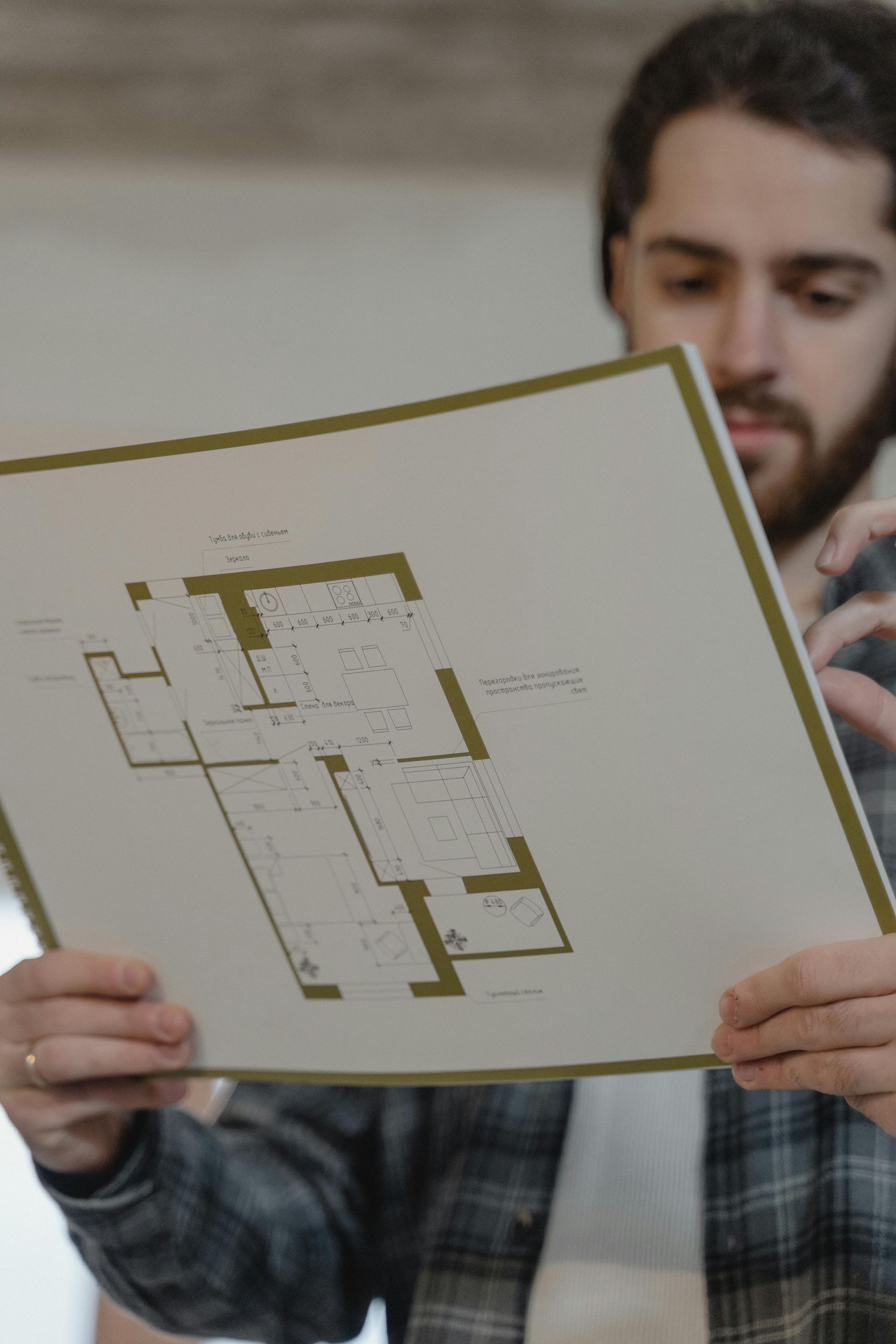 Person holding up a floor plan drawing in a room