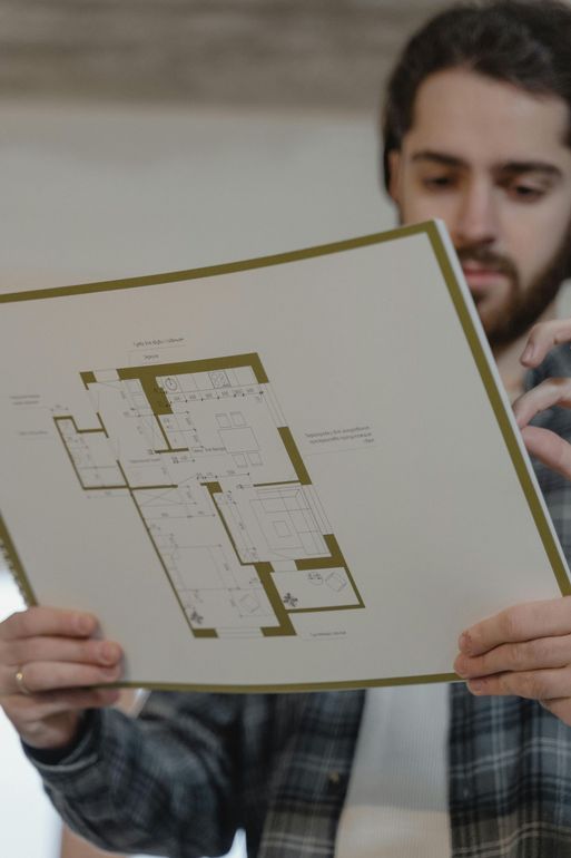 Person holding up a floor plan drawing in a room
