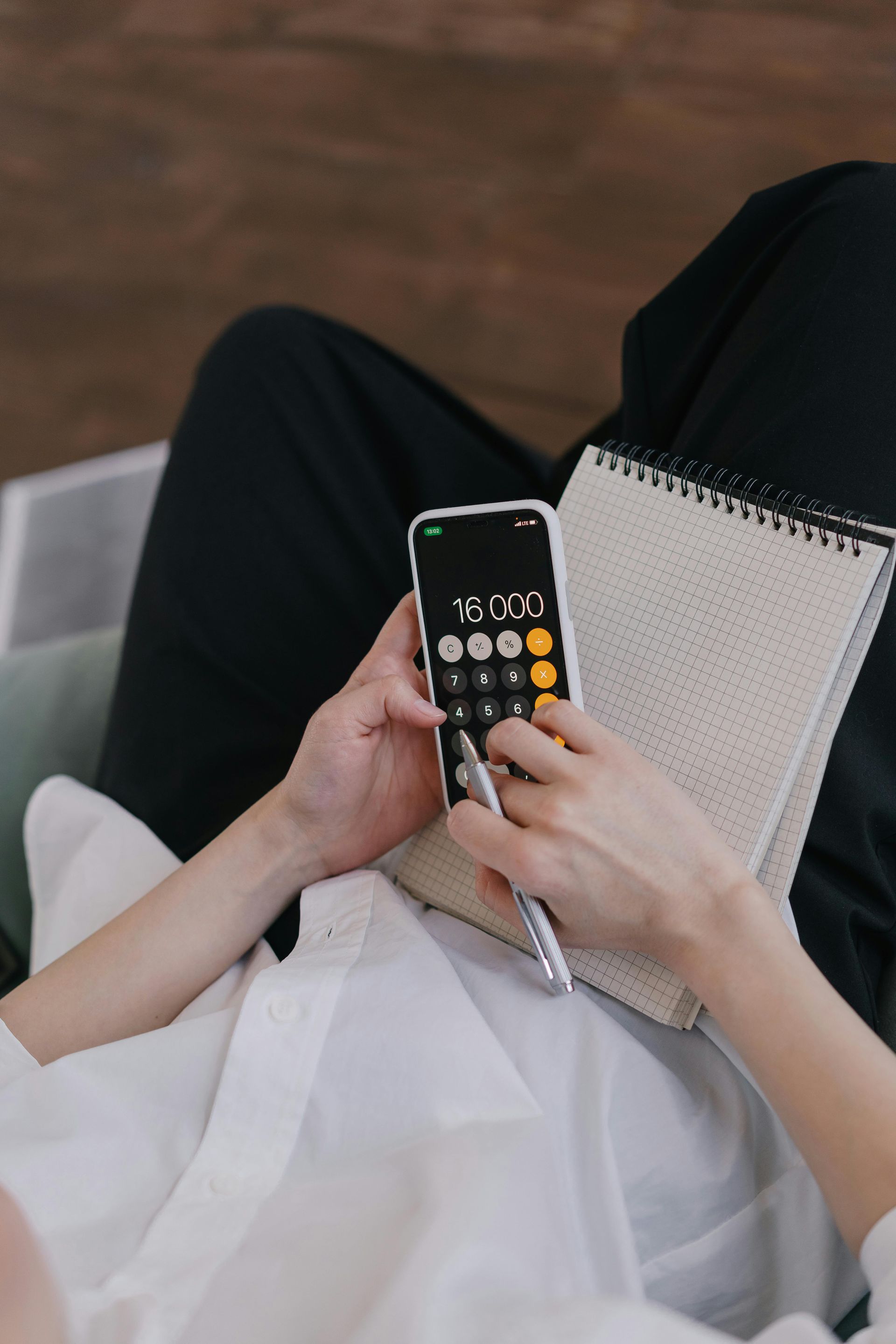 Person holding a calculator and notebook while sitting on a couch