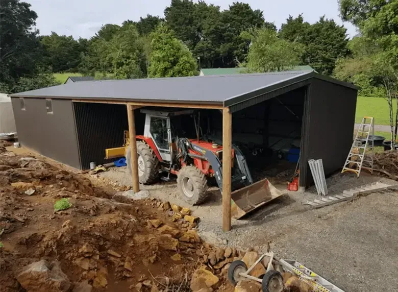 A tractor is parked under a canopy in a garage.