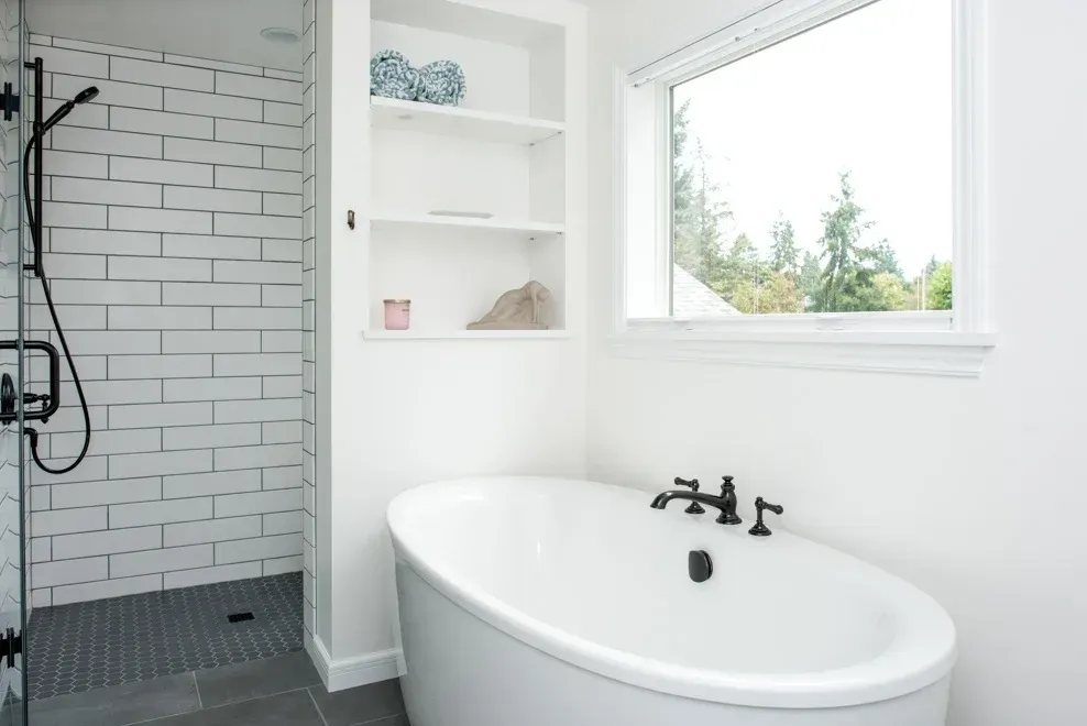 A bathroom with a tub , shower , and window.