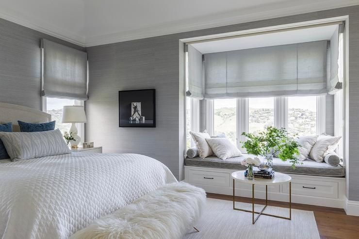 A bedroom with a bed and a window seat.