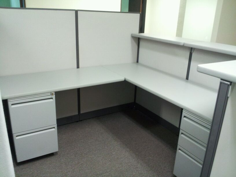 An empty office cubicle with a desk and drawers