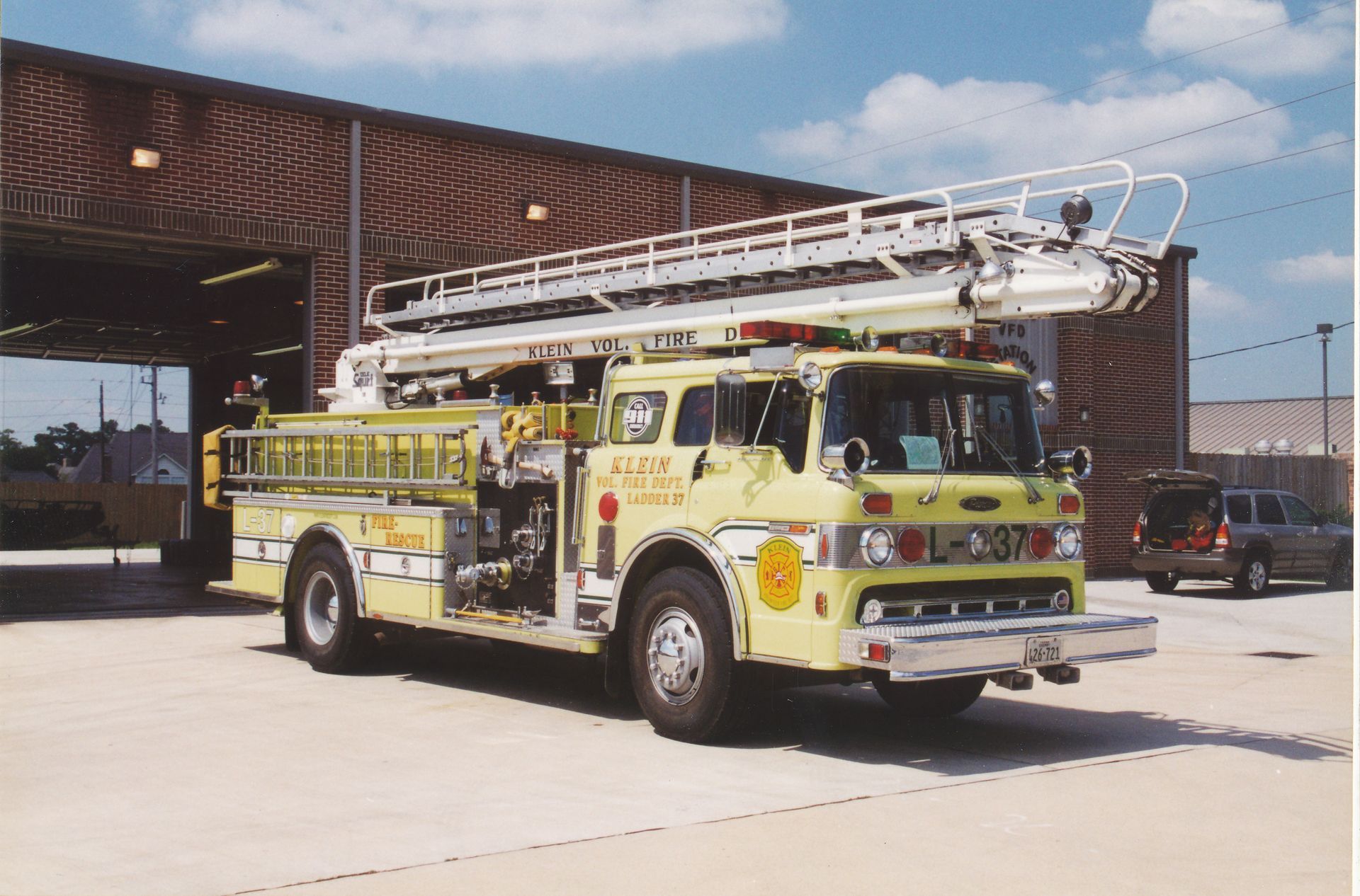 Yellow ladder fire truck parked outside a fire station