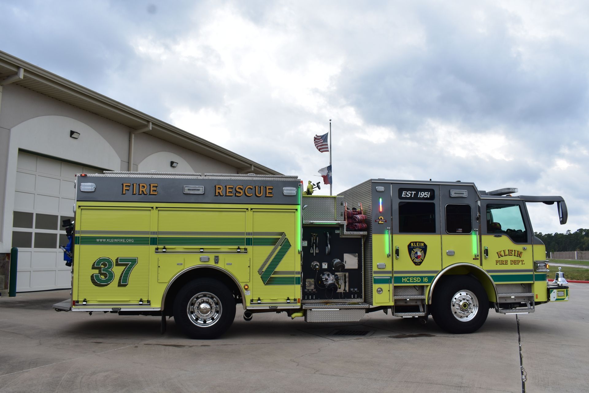 Bright lime-green and yellow fire truck parked outside a station under cloudy skies