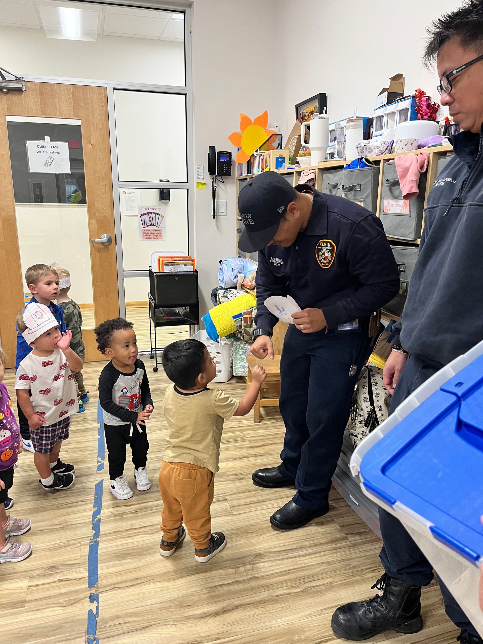 A fire fighter is talking to a group of children in a room.
