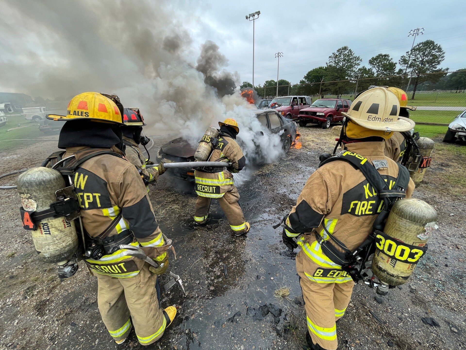 A group of fire fighters are putting out a car fire.