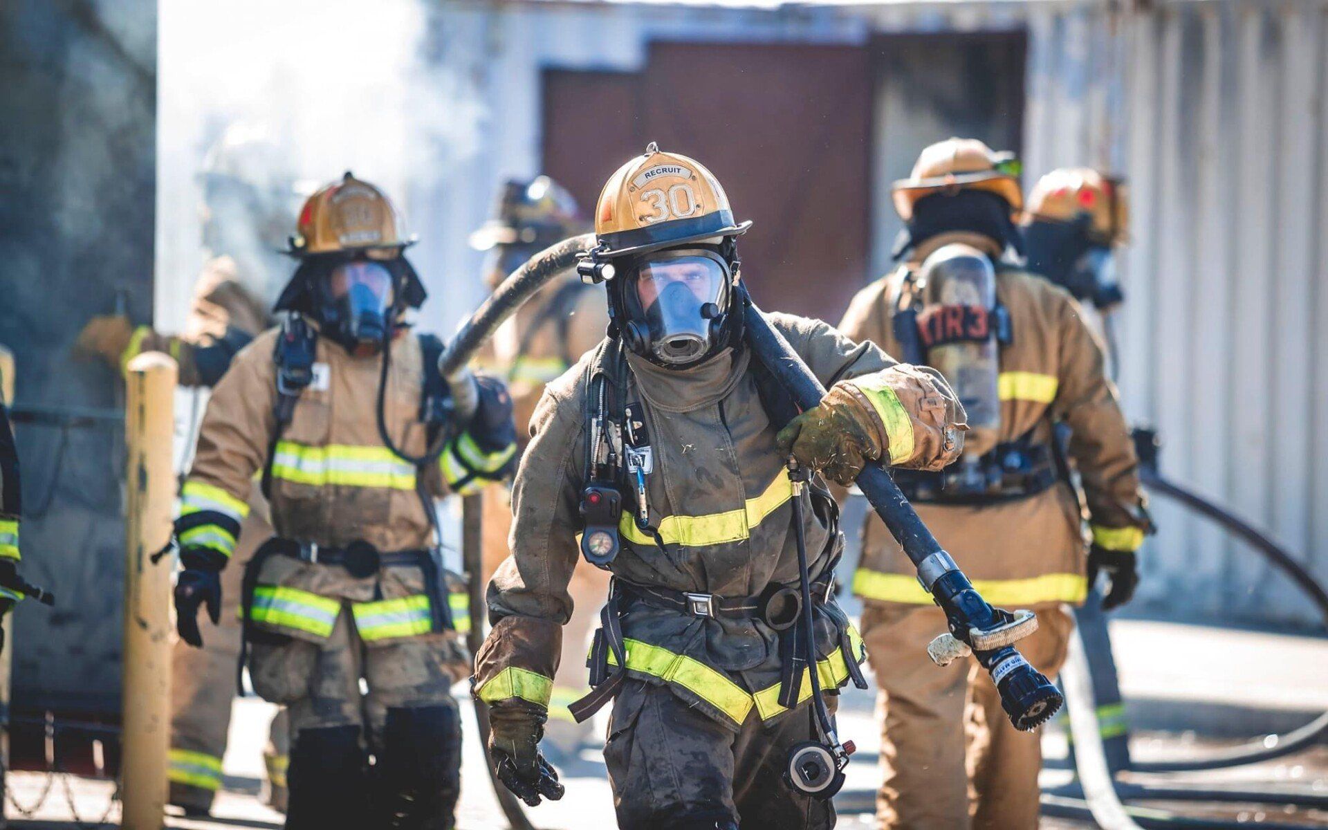 A group of firefighters are fighting a fire with a hose.