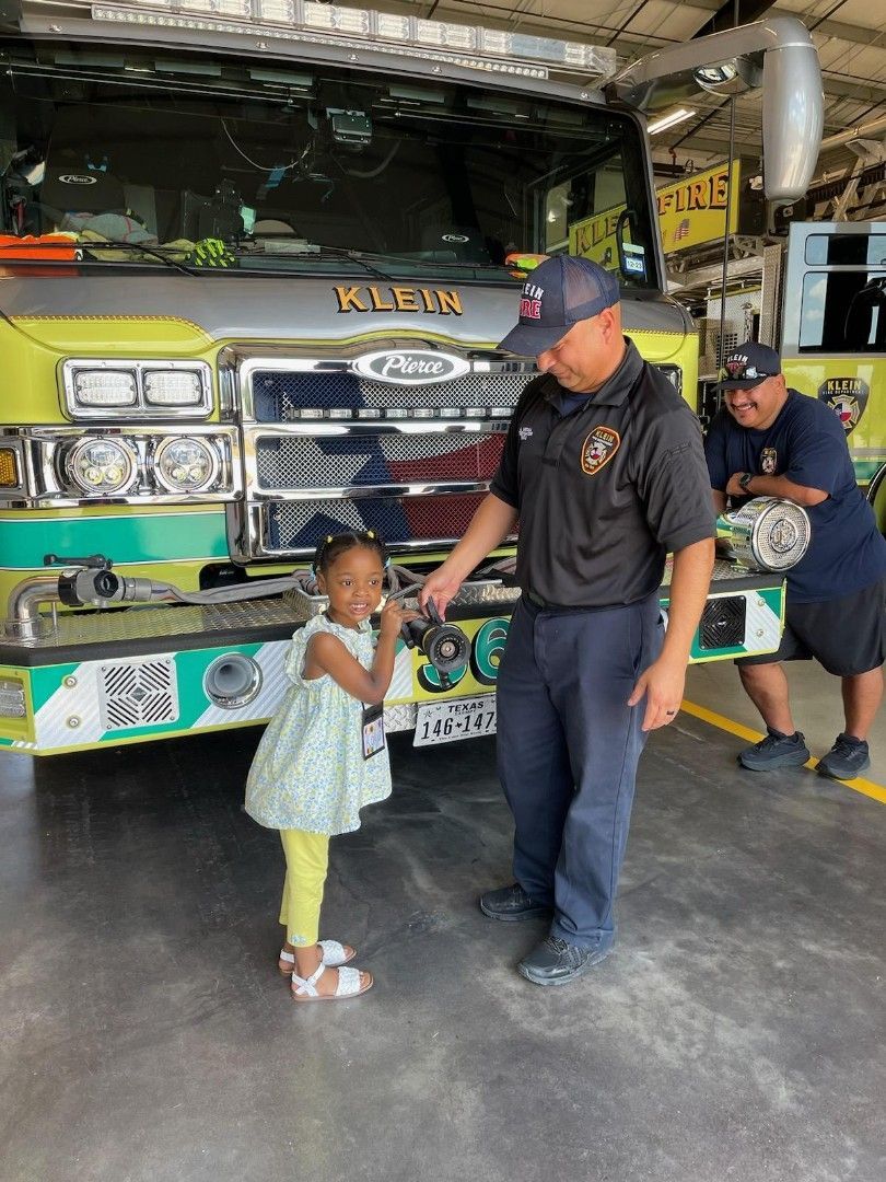 A man and a little girl are standing in front of a fire truck.