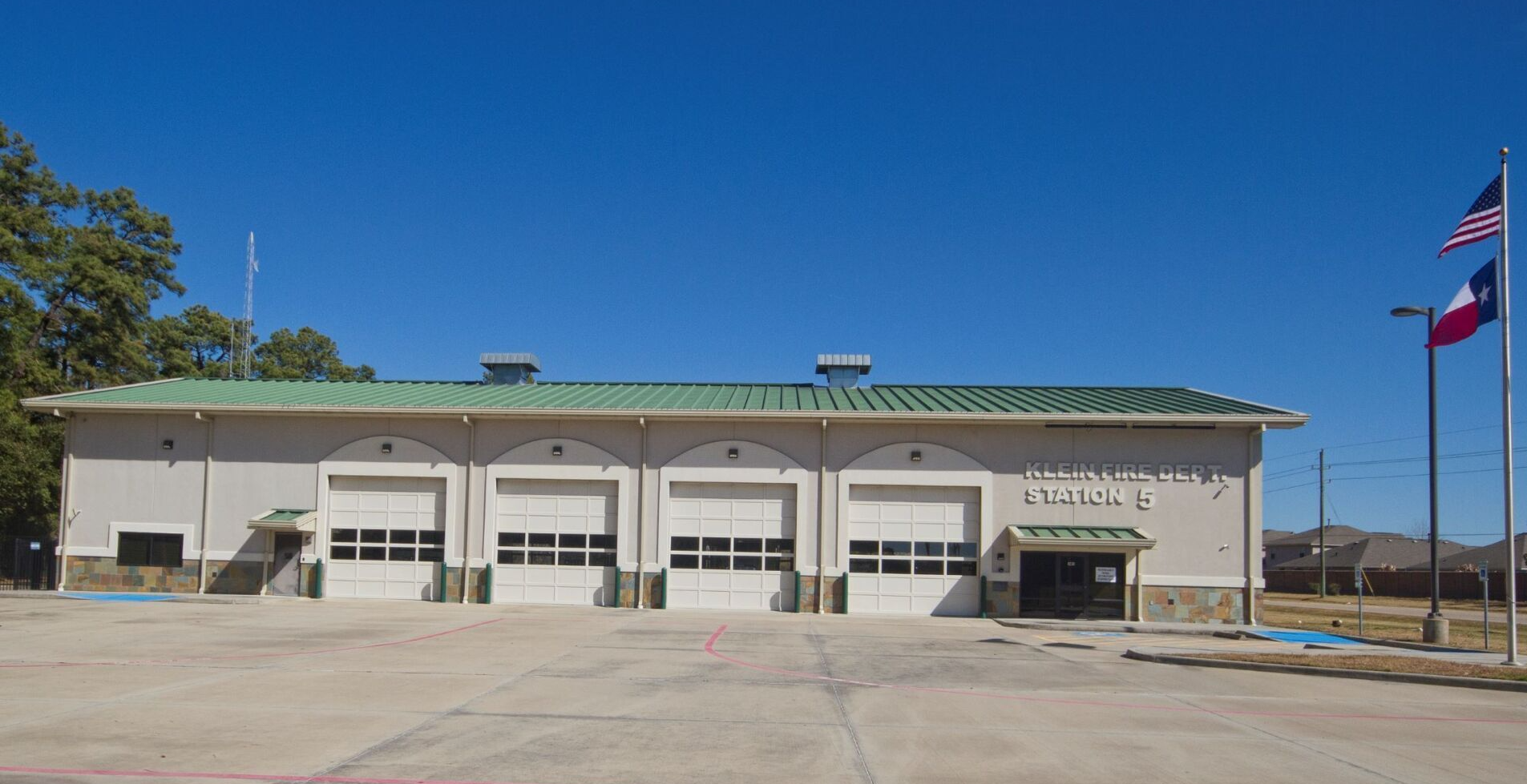 A large white building with a green roof and a Texas flag in front of it.