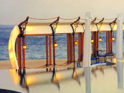 A swimming pool with a row of umbrellas overlooking the ocean.