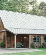 White siding building with French doors and two small square windows, set against a background of trees.