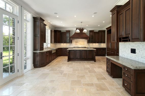Large, luxurious kitchen with dark brown cabinets, beige tile floor, and large French doors.