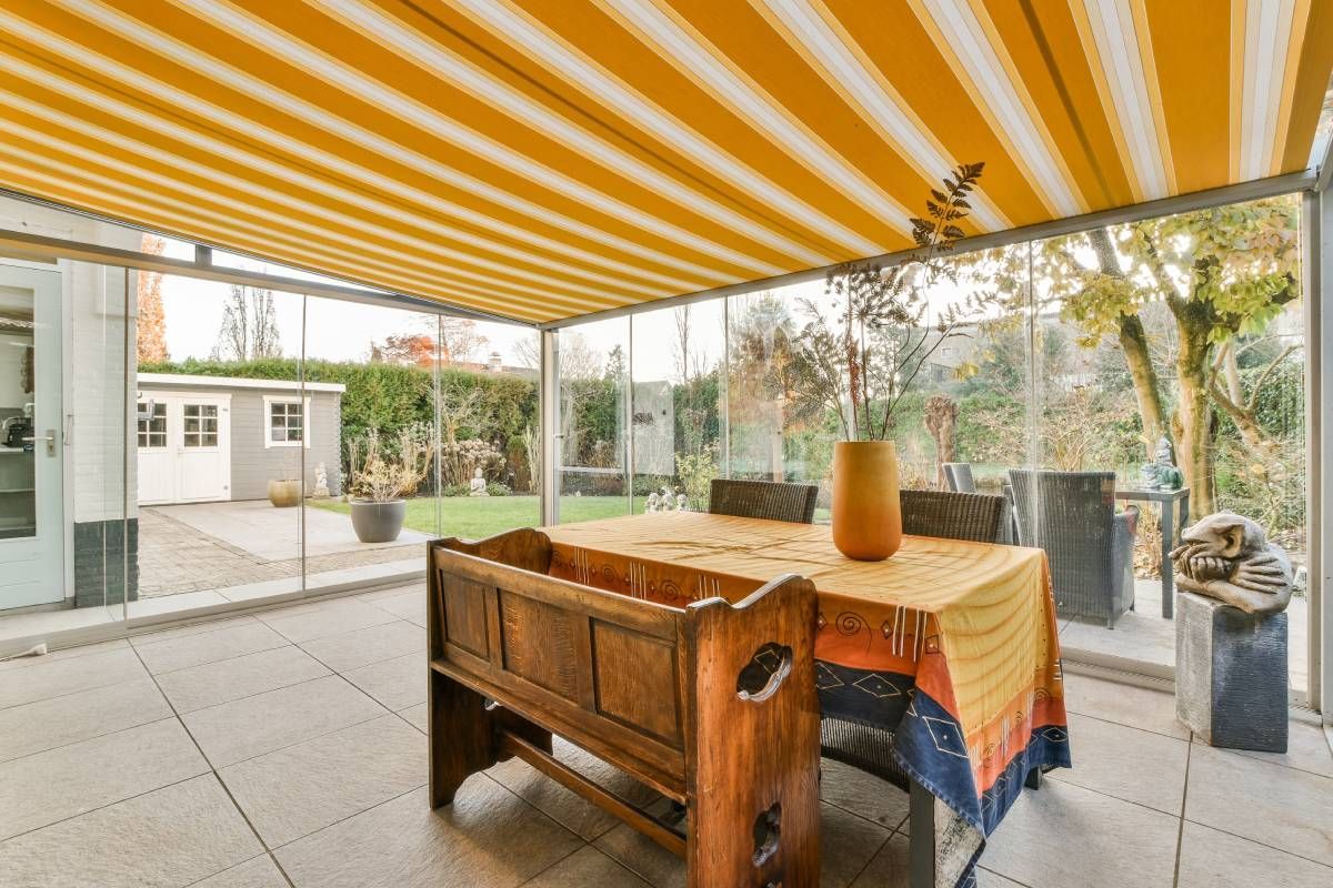 A sunny yellow and white striped awning covering a large patio with charming outdoor furniture near Lewiston & Moscow, ID and Clarkston & Pullman, WA