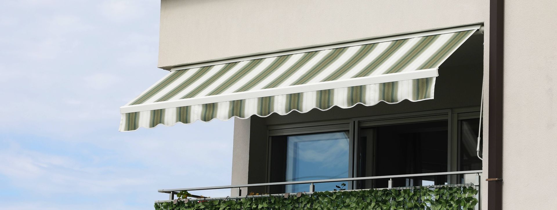 Image of a white and green striped sun awning on a home's balcony