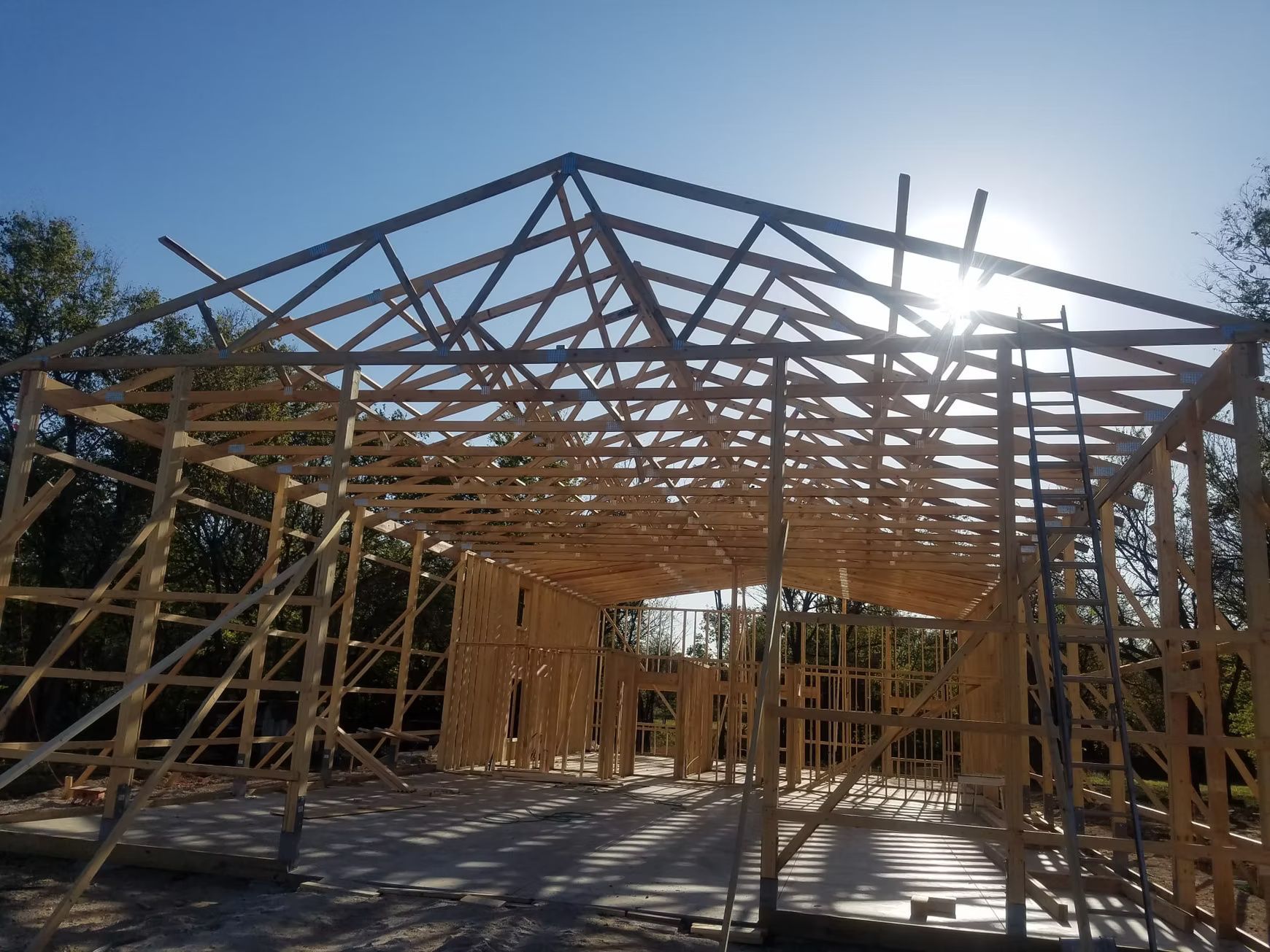 Wooden frame of a building under construction; sun shining through the roof trusses.