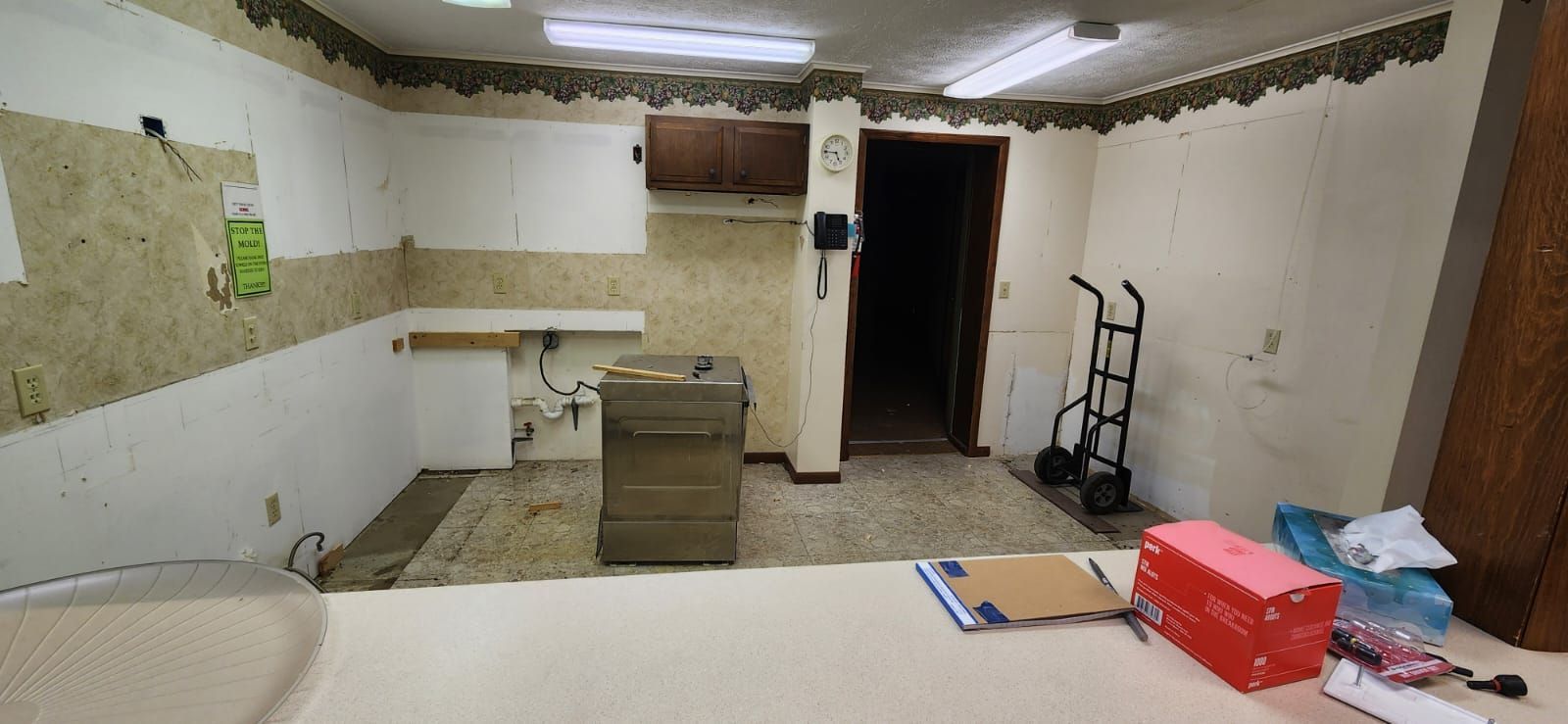 A room under renovation with bare walls, a standalone file cabinet, a hand truck.
