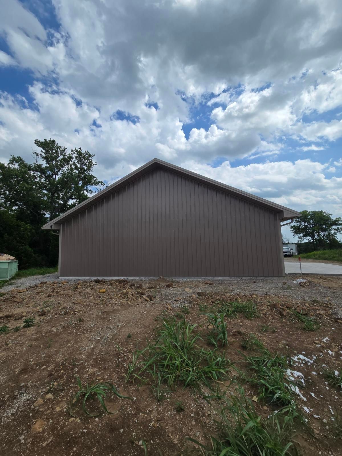 Brown barn-like building on a dirt lot under a cloudy sky