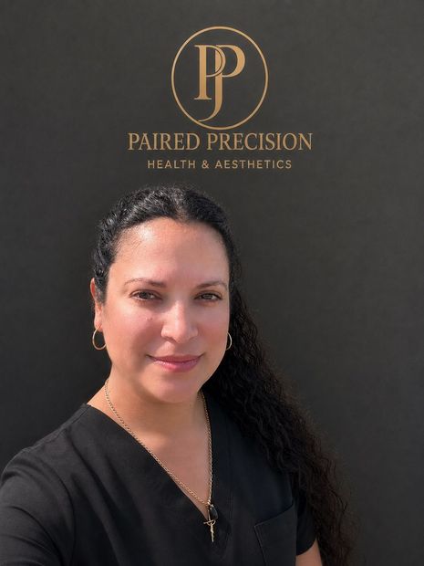 Woman in white coat stands in front of a logo with a golden halo.