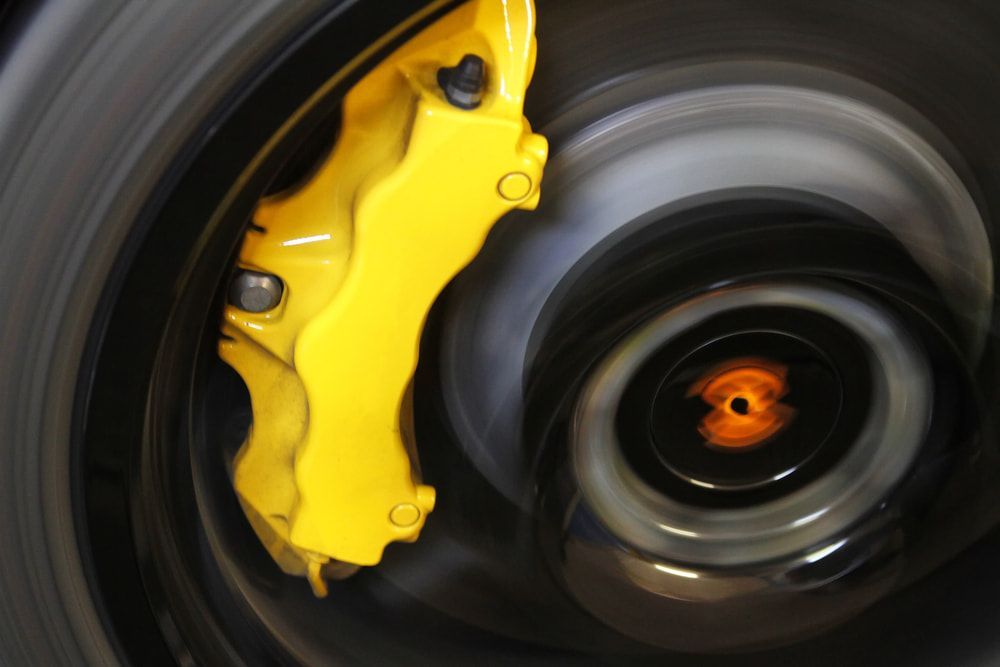 A Close Up Of A Yellow Brake Caliper On A Car Wheel — Carson's Car Care In Armidale, NSW