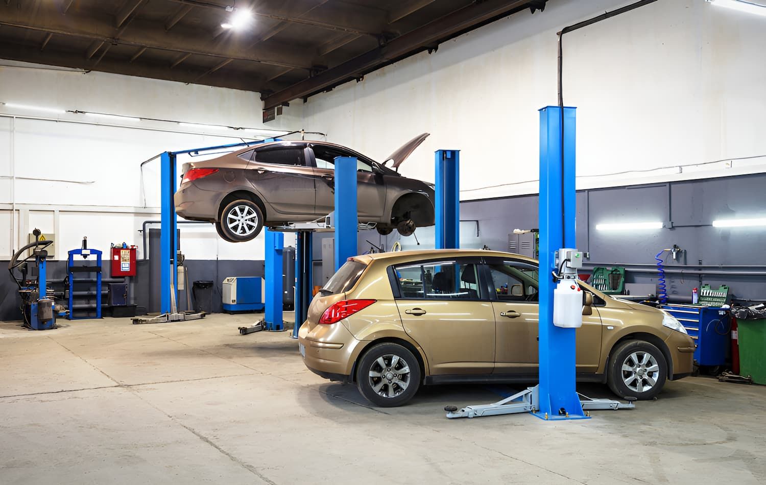 Two Cars Are On Lifts In A Garage — Carson's Car Care In Armidale, NSW