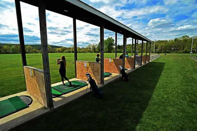 A woman is swinging a golf club at a golf course.