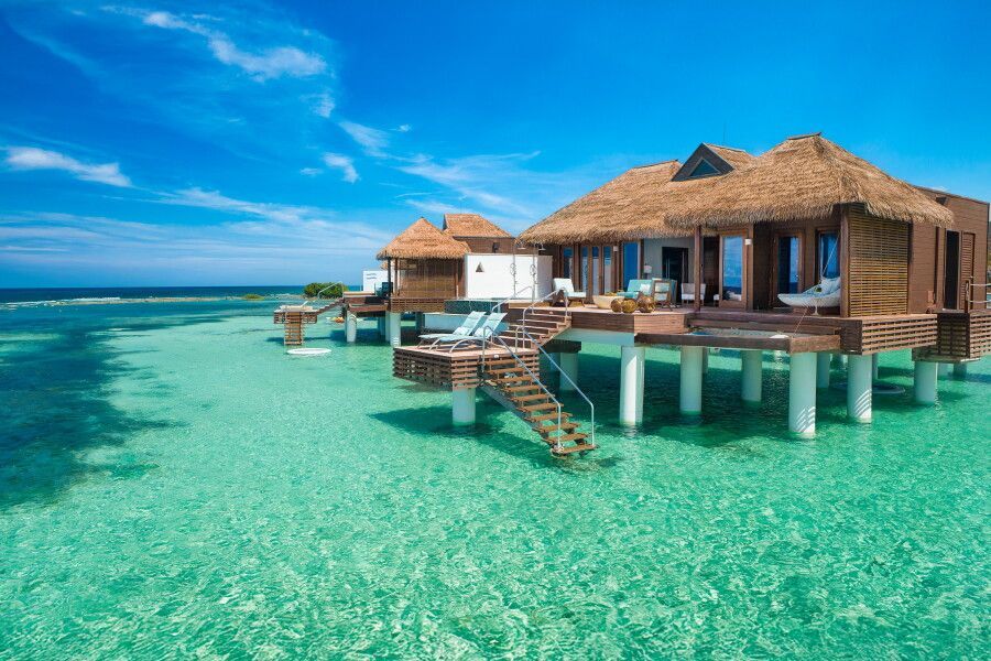 Overwater tropical bungalow on turquoise sea with wooden deck and bright blue sky