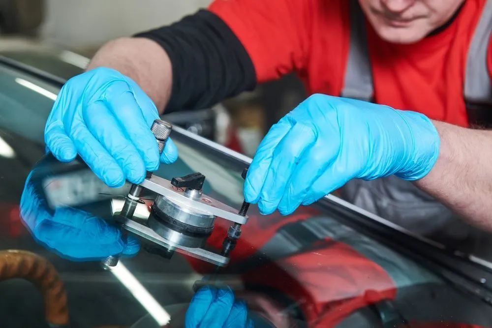 Person in Blue Gloves Using a Tool to Repair a Windshield Crack — Southern Tablelands Windscreen Repairs in Crookwell, NSW