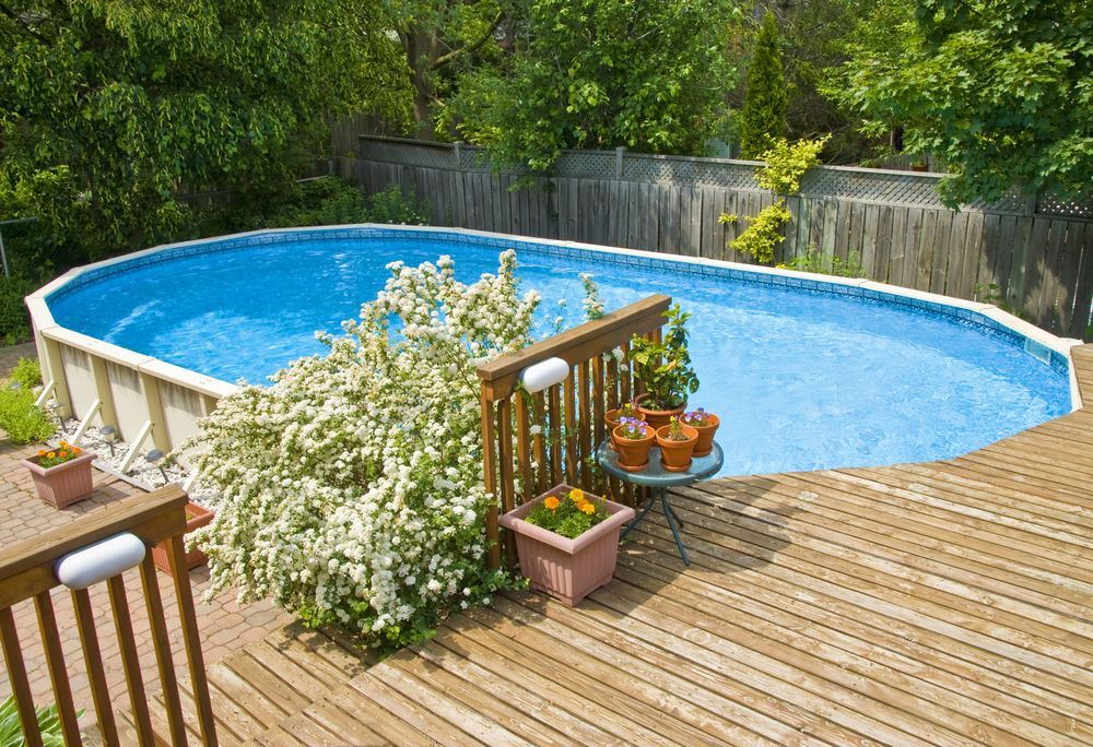 Above-ground oval pool with a wooden deck, surrounded by a fence and lush greenery — Tweed Pool Shop in Tweed Heads South, NSW