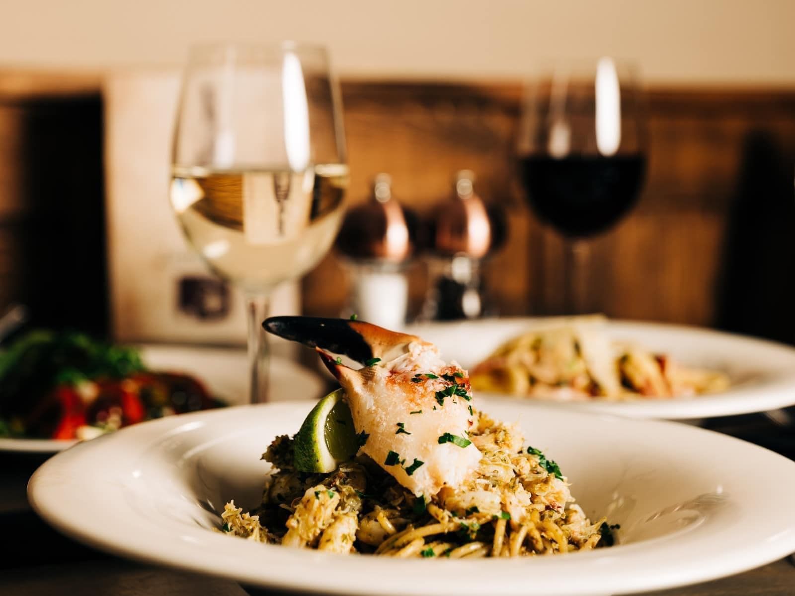 A plate of food and two glasses of wine on a table.