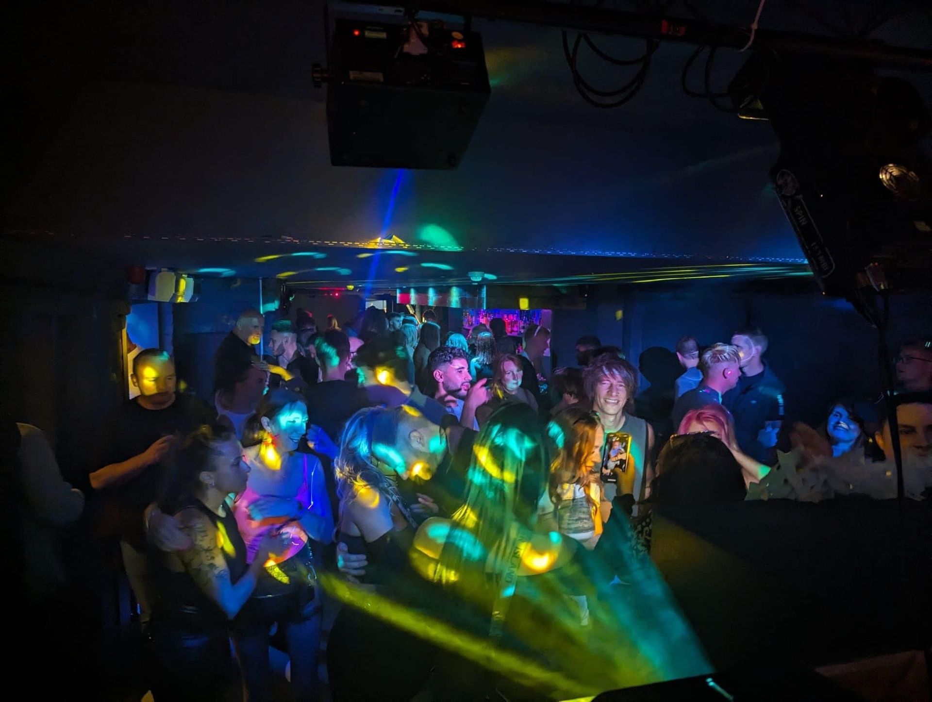 A crowd of people are dancing in a dark room at a disco.