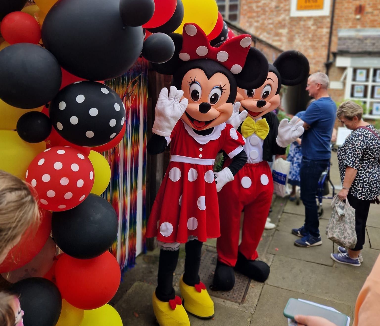 A couple of mickey mouse mascots standing next to each other