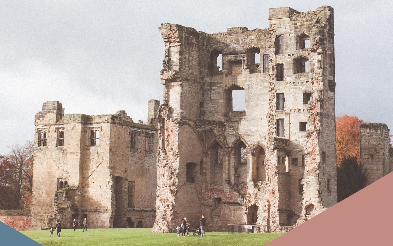 A group of people are standing in front of a ruined castle.