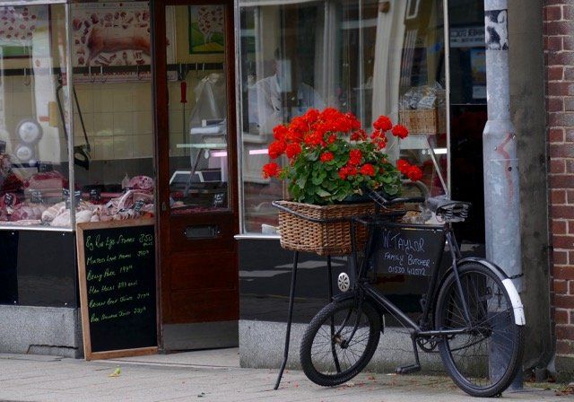A bicycle is parked in front of a butcher shop