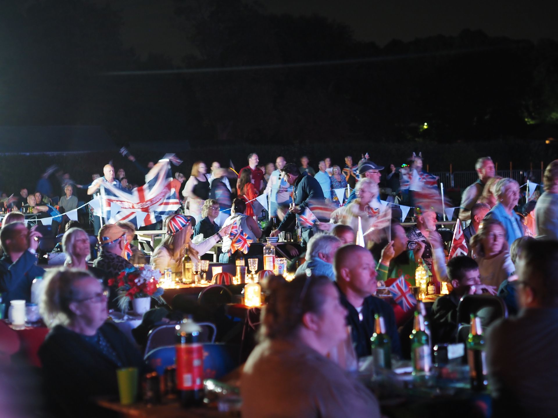 A crowd of people are sitting at tables in a dark room
