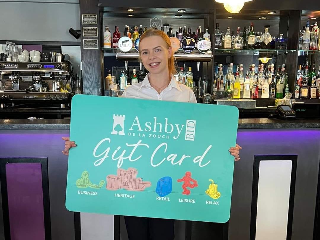 A woman is holding a gift card in front of a bar.