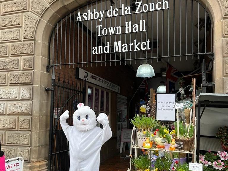A bunny mascot is standing in front of the ashby de la zouch town hall and market.