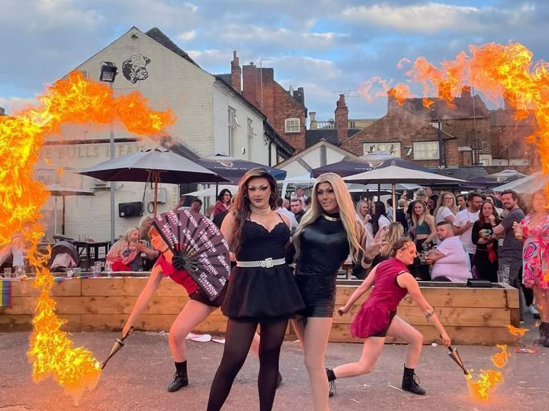 A group of women are dancing in front of a crowd with fire coming out of their fans.