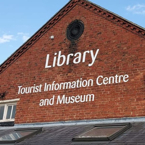 A brick building with a sign that says library tourist information centre and museum