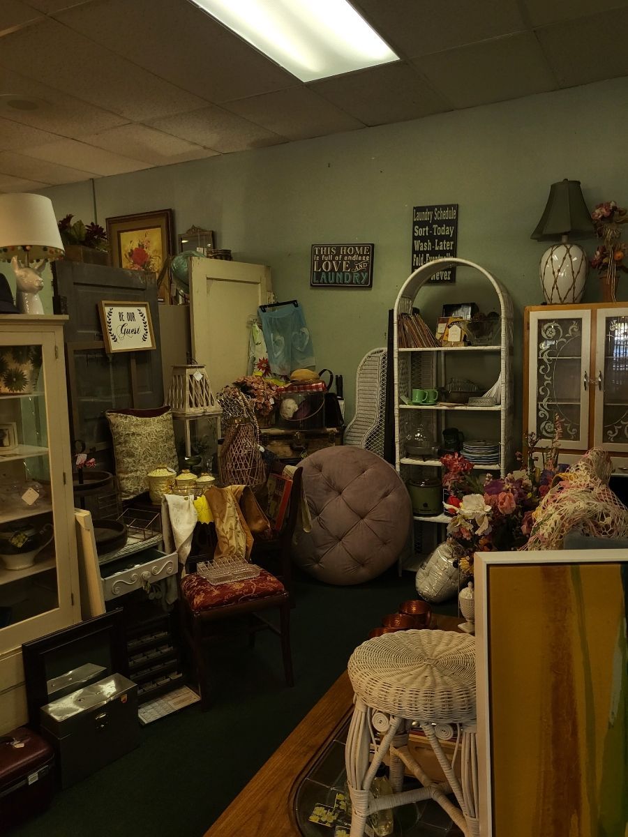 A cluttered antique shop interior; cabinets, furniture, and various items on display.