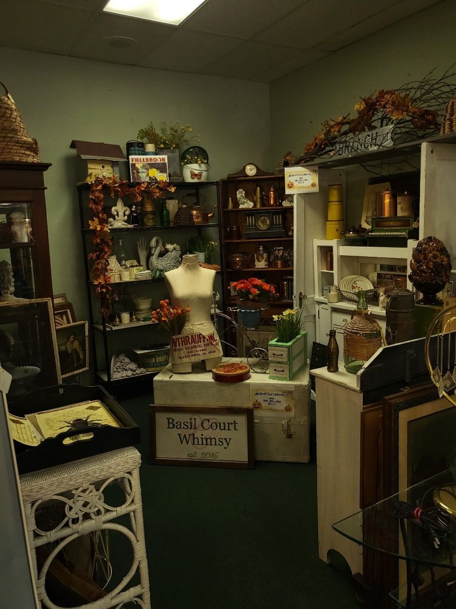 Antique store interior, featuring display cases, mannequin, and various vintage items with dark green carpet.